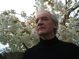 Seamus Deane photographed in front of cherry blossoms.